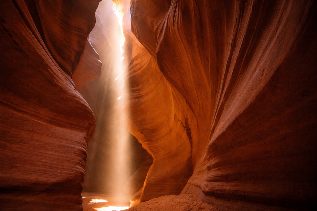Warm light beams falling between the sculpted sandstone walls of a slot canyon near Page, Arizona