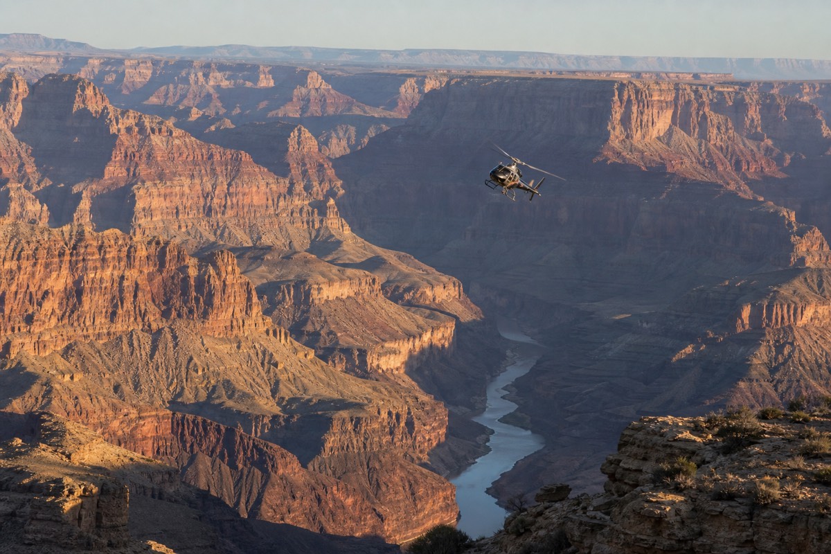 A sightseeing helicopter flying above the Grand Canyon with the Colorado River glinting deep in the gorge